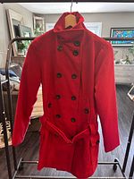 Front view of red double-breasted belted peacoat on hanger