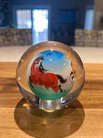 Front view of clear glass paperweight with interior horse painting