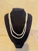 Full view of necklace draped on bust form showing pearl strand