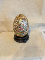 Front view of painted porcelain egg on wooden stand