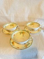 Front view of three handled soup cups on saucers