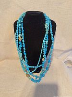 Front view of multi-strand turquoise bead necklace on display bust