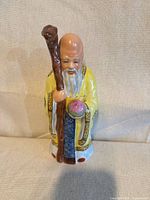 Front view of porcelain Shou figurine showing staff, peach, robe colours
