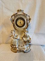 Full view of porcelain mantel clock with figures and dial