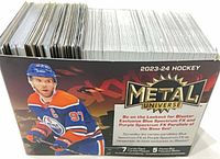 Full box of stacked 2023-24 Metal Universe cards showing Connor McDavid art on box