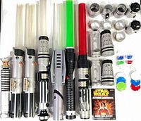 Group view of seven lightsabers, lightsaber remote, modular hilt parts, coloured discs and booklet