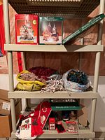 Overall view of shelving with boxed village houses, silhouette light box, lights, garland and linens