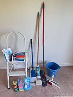Full lot showing ladder, long-handle tools, bucket and packaged cleaners