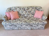 Front view of floral sofa with three pink pillows