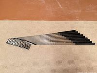 Full view of nine irons fanned out showing clubheads, shafts and grips