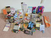 Overall spread of all craft items on carpet showing trimmer, tubs, ribbons, stickers, paper, sequins