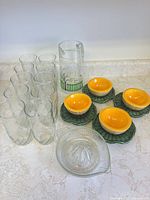 Group shot of all items: 8 glasses, pitcher, 4 bowl/saucer sets, reamer
