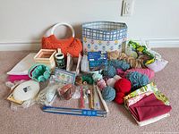 Entire lot overview showing yarn, fabric, plastic canvas items, needles, notions and storage bin