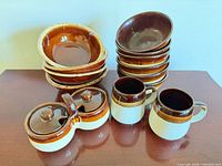 Front angled view showing entire set: stacked bowls, mugs, double condiment dish with lids
