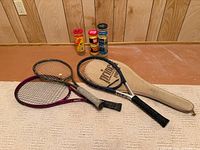 Overview of three racquets, ball cans and cover