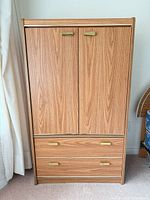 Front view showing two doors and two drawers with brass-tone pulls