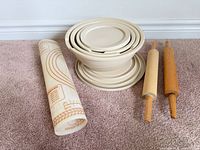 Lot overview showing rolled pastry mat, stacked bowls with lids, two rolling pins