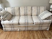 Front view of beige and blue-gray striped 3-seat sofa with two matching pillows