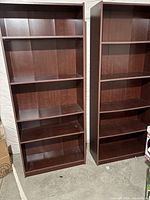Two cherry laminate bookcases with adjustable shelves