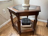 Overall view of hexagonal brown wood end table with glass top and lower shelf