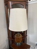 Full view of lamp showing amber glass base, metal fittings, and fabric shade