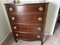 Front view of mahogany dresser showing four drawers and brass oval pulls