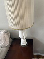 Full view of lamp on side table showing ceramic base and pleated shade