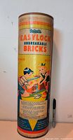 Front of cylindrical container showing brand, product name and illustration