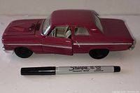 Side view of maroon 1964 Ford diecast, doors closed, Sharpie for scale