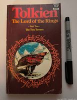 Front cover of 1970s paperback alongside marker for scale