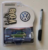 Front view of sealed GreenLight Club V-Dub 1979 Volkswagen Rabbit die-cast car on card with pen for scale