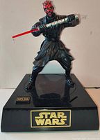 Front view of Darth Maul bank on base showing figure pose and lightsaber