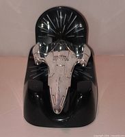 Front view of silver starship hovering over black base