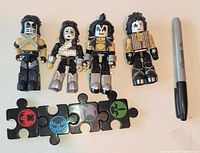 Four Kubrick KISS figures with puzzle stands and Sharpie for scale