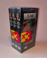 Front angled view of sealed 3-pack T-160 VHS tapes showing graphics, T-160 marking and VHS logo