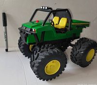 Front angled view of John Deere Monster Treads Gator toy showing wheels, body and marker for scale