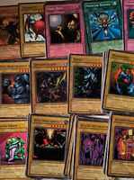 Group of unsleeved Yu-Gi-Oh! cards with titles such as Trap Hole, Monster Reborn, Swordstalker, Trent visible