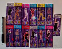 Thirteen Cadbury Spice Girls wrappers laid out beside marker for scale