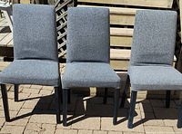 Front view of three matching grey upholstered chairs