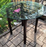 Full view of table showing glass top and legs outdoors