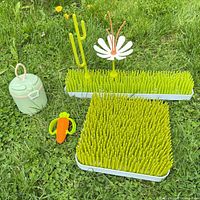 Complete set displayed on grass: square and rectangular drying racks, flower and cactus stems inserted, carrot teether, small container