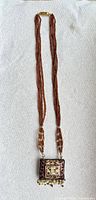 Full view of long multi-strand bead necklace with pendant and clasp