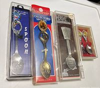 Front view of four packaged souvenir flatware items