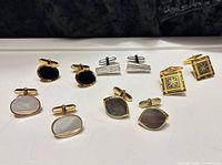 All five pairs of cufflinks laid out to show variety of shapes and materials