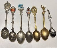 front view of 7 souvenir teaspoons