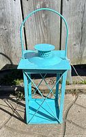Full view of turquoise metal lantern standing upright