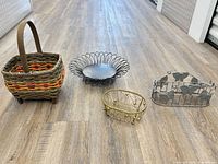 Group view of wicker basket, black wire bowl, gold basket tray, silver butterfly napkin holder