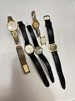 All seven wristwatches laid out showing bands and dials