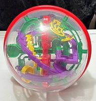 Front view of Perplexus Rookie sphere showing red equator band and multicolor track