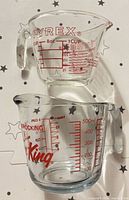 Front view of both measuring cups showing logos and graduations